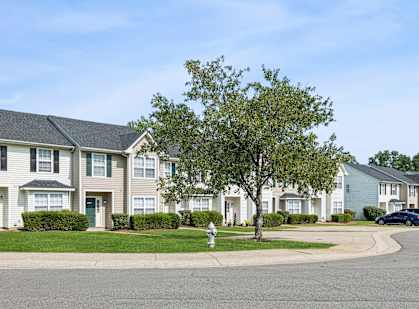 A row of houses with a tree in front of the first one.