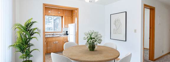A dining room with a round table and chairs. Fargo, ND L&R Apartments