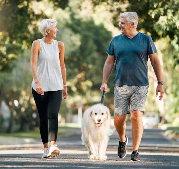 an older couple walking their dog in the park