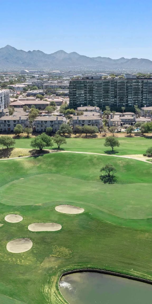 A golf course with a lake and apartment buildings in the background.