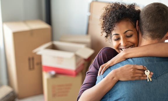 a couple hugging in a room full of boxes