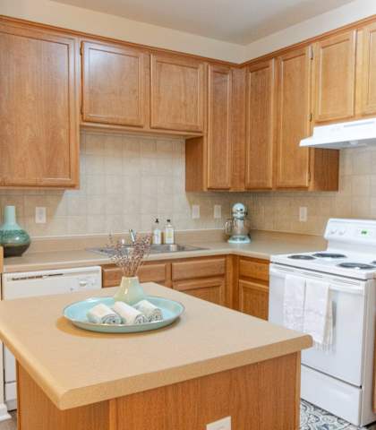 A kitchen with wooden cabinets and a white stove top oven.