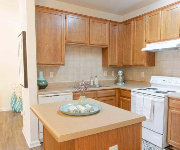 A kitchen with wooden cabinets and a white stove top oven. at The Crest at Sugarloaf, Lawrenceville, GA, 30044