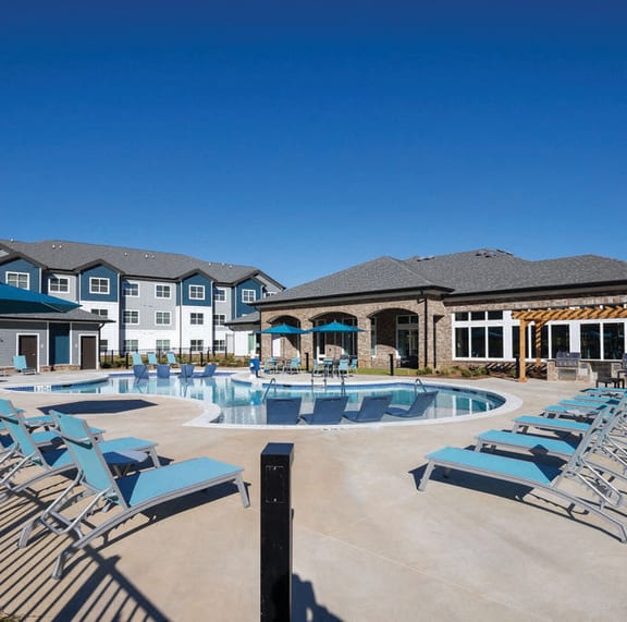 a swimming pool with blue lounge chairs in front of a building at Fairview Springs in Covington, GA, 30016