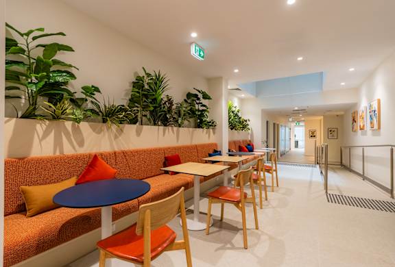 a lobby with orange couches and tables and chairs