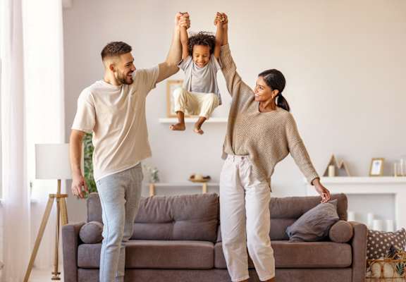 A family of three is playing in a living room.