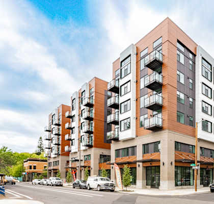 A modern apartment building with a parking lot in front.