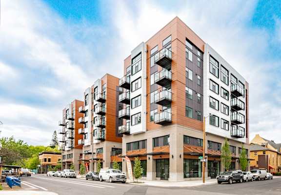 A modern apartment building with a parking lot in front.