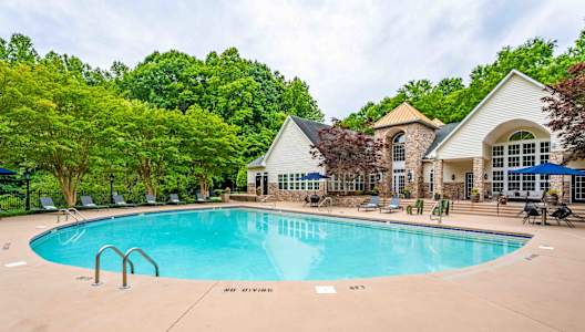 a swimming pool with a house and trees in the background