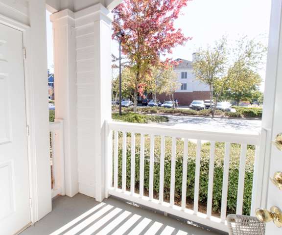 A white door is open to a balcony with a white railing. at The Crest at Sugarloaf, Lawrenceville