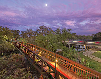 A wooden bridge over a river with a full moon in the sky.