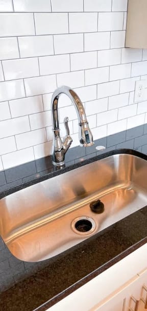 a stainless steel sink in a kitchen with white tiles