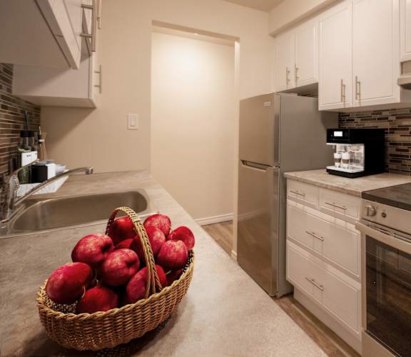 A kitchen with a refrigerator, oven, and sink.