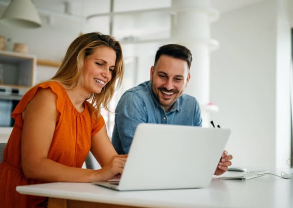two people sitting at a table looking at a laptop computer