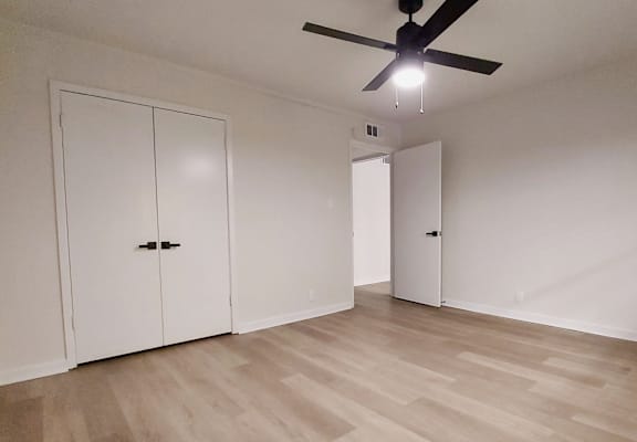 an empty living room with white walls and a ceiling fan