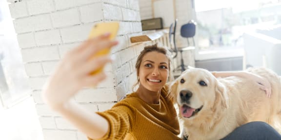 a woman and her dog taking a picture with her cell phone