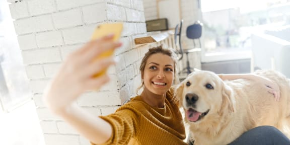 a woman and her dog taking a picture with her cell phone
