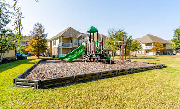 A playground with a green slide and a wooden structure.