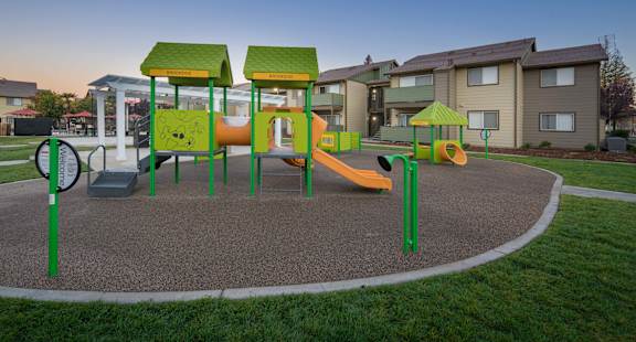 A playground with a yellow slide and green play structures.