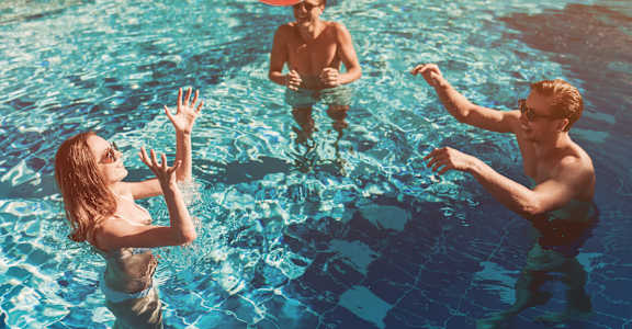 A group of people playing with a beach ball in a pool.