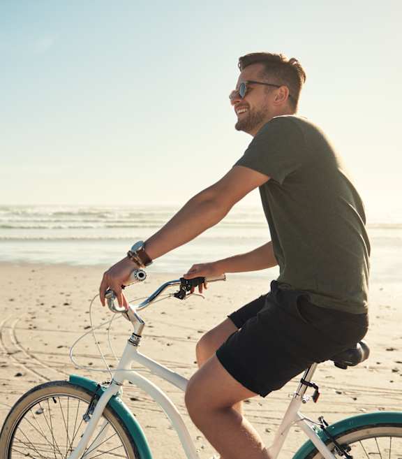 A man is riding a bicycle on the beach.