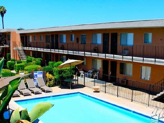 A pool and patio area in front of a building with orange walls.