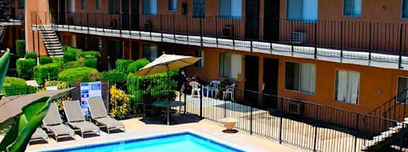 A pool and patio area in front of a building with orange walls.