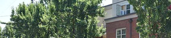A red car is parked in front of a brick building.