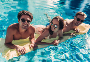 three people in a swimming pool wearing sunglasses