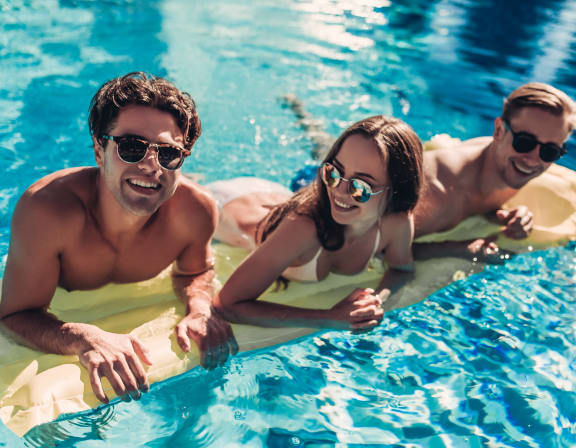 three people in a swimming pool wearing sunglasses