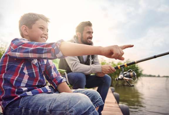 A young boy and a man are fishing on a dock.