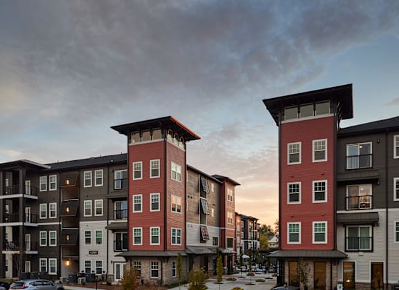 Two red and white buildings with balconies in front of a cloudy sky.