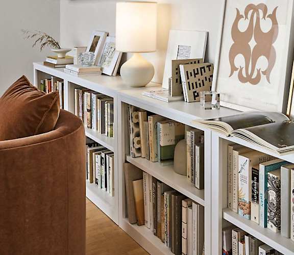 a living room with a book shelf filled with books and a chair