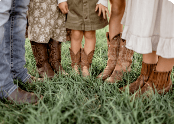 A group of people standing in grass wearing boots.