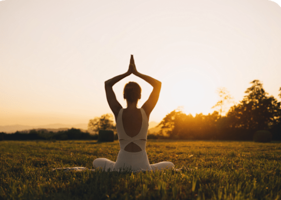 Woman Practicing Yoga in Grassy Field During Sunset