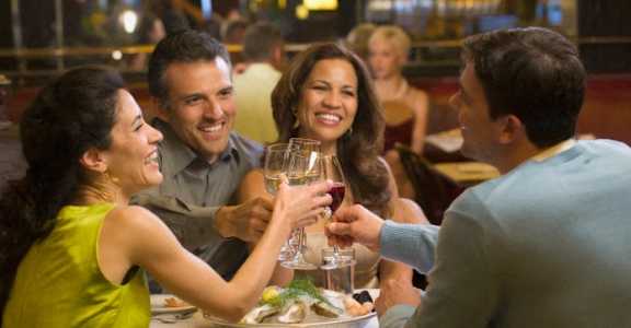 A group of people toasting with wine glasses at a restaurant table.
