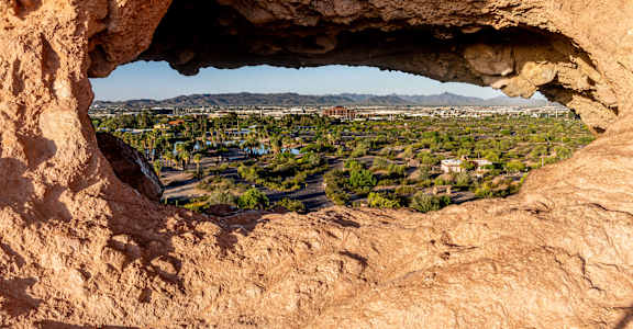 a hole in the rock with a view of the city of palm springs