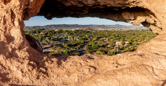a hole in the rock with a view of the city of palm springs