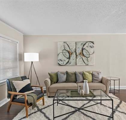 A living room with a couch, chair, and a painting on the wall.