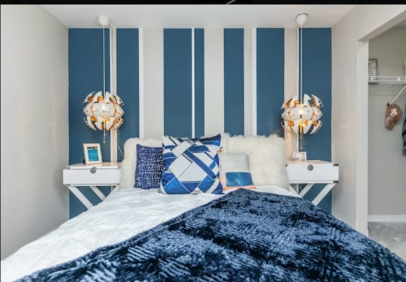 A bedroom with a white bed and blue and white striped walls.
