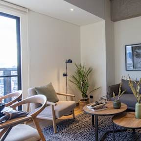 A living room with a grey couch, a wooden table, and a potted plant.