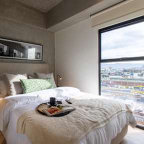 A bedroom with a large bed and a view of the city.