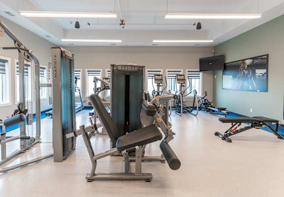 A gym with a variety of equipment including a leg press machine. at Vista Apartments at Edgemont, Edmonton, AB