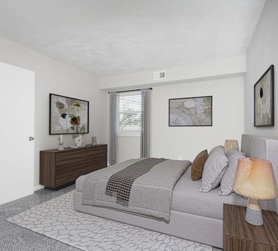 A bedroom with a bed, nightstand, and artwork on the wall.