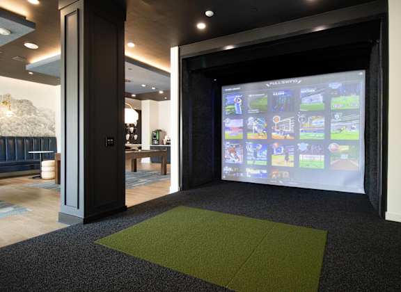 A room with a green carpet and a screen with images on it. at The Crest at South Point Apartments, McDonough, GA