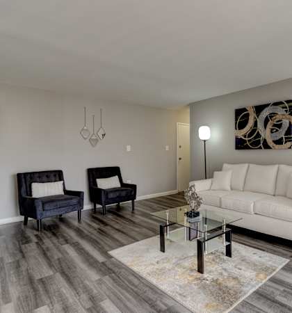 A living room with a white couch, a black chair, and a glass coffee table.