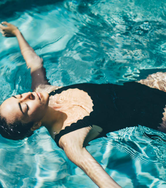 A person in a black swimsuit is floating in a pool.