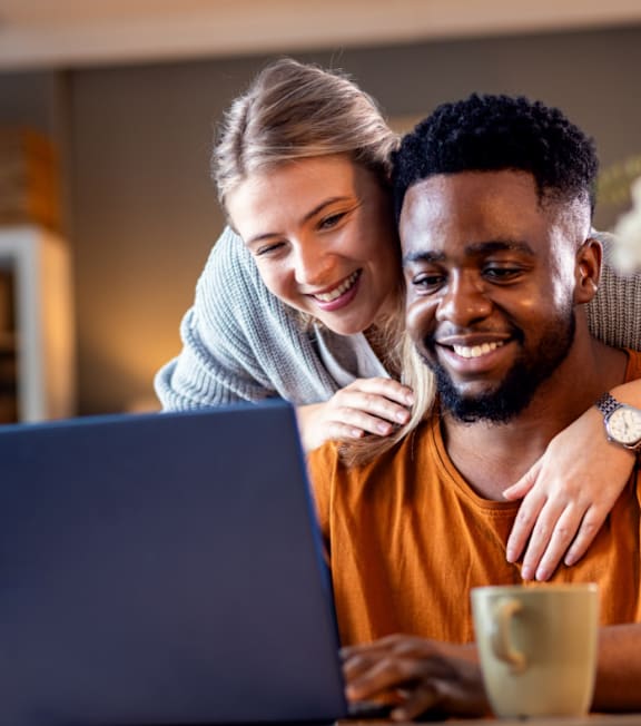 A man and a woman are looking at a laptop screen together.