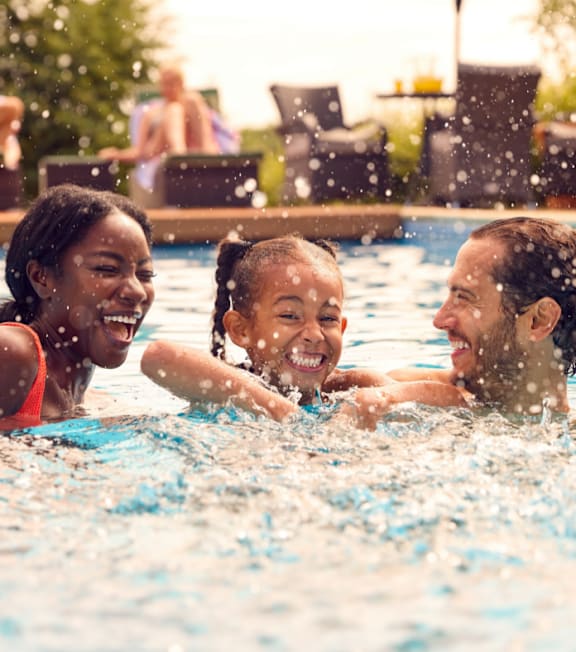 Family Smiling and Having Fun Playing in Swimming Pool Together