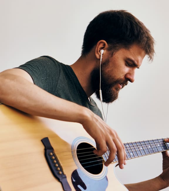 A man with earphones playing a guitar.